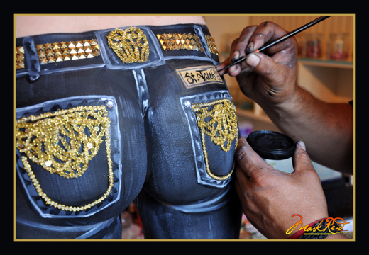 close up picture of the rear of a woman being painted with blue jeans and gold highlights